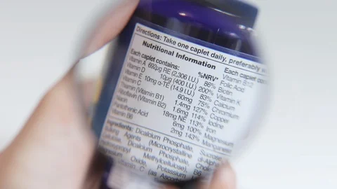 Examining nutritional information label on a bottle of supplements Stock Footage 121888599