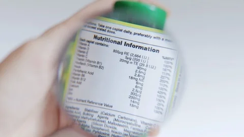 Examining nutritional information label on a bottle of supplements Stock Footage 121888897