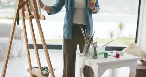 Examining paint jars painter is dipping brush into yellow then green paint and 库存影片 343239847