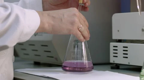 Examining sample and mix magenta liquid in flask Vidéo 52074633