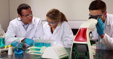 Examining samples scientists in coats and goggles using microscope in lab, with Foto stock