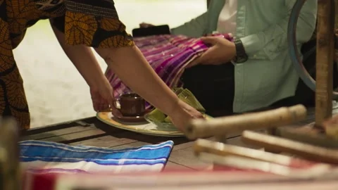 Examining silk fabric then serving traditional Bugis food Stock-Footage 345860171