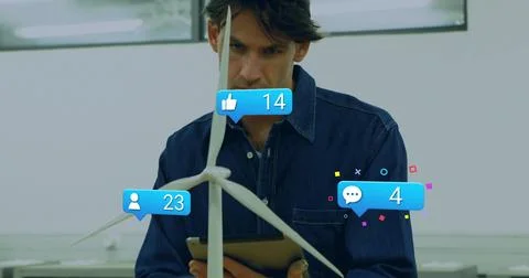 Examining wind turbine, engineer in dark button-up with tablet at bright lab Stock Photos