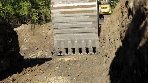 An excavator is actively digging and moving large amounts of dirt at a Stock Footage 312172529