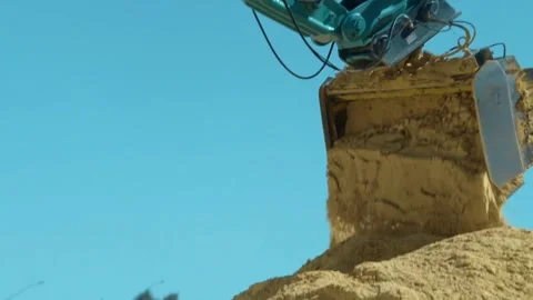 An excavator is actively operating on sandy terrain, showcasing the power of Stock Footage 312451882