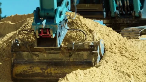 An excavator is actively working on sandy ground at a busy construction site Stock Footage 312451862