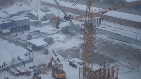 Excavator and a crane working on a construction site during a snow blizzard, 4k Stock Footage 71580222