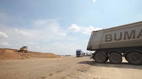 Excavator and trucks driving, digging and loading dirt on a construction yard Stock Footage 136569331