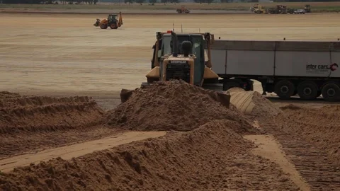 Excavator and trucks driving, digging and loading dirt on a construction yard Stock Footage 136573659