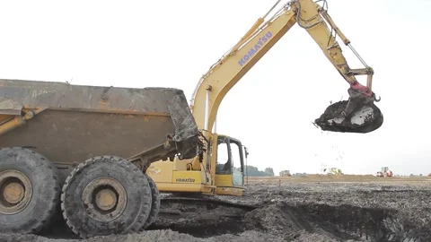 Excavator and trucks driving, digging and loading dirt on a construction yard Stock Footage 136735552