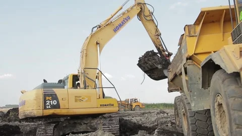Excavator and trucks driving, digging and loading dirt on a construction yard Stock Footage 136745552