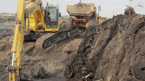 Excavator and trucks driving, digging and loading dirt on a construction yard Stock Footage 136747357