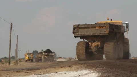 Excavator and trucks driving, digging and loading dirt on a construction yard Stock Footage 136825855