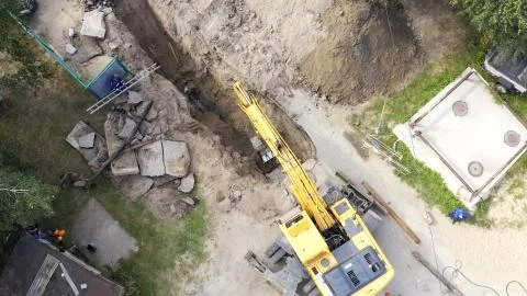 Excavator and workers digging a pipe hole Stock Photos