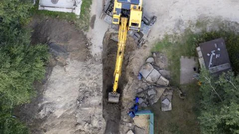 Excavator and workers digging a pipe hole Foto stock