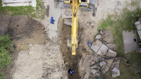 Excavator and workers digging a pipe hole Foto stock