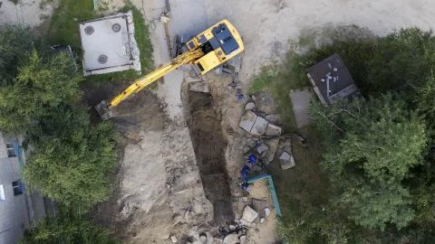 Excavator and workers digging a pipe hole Stock Photos