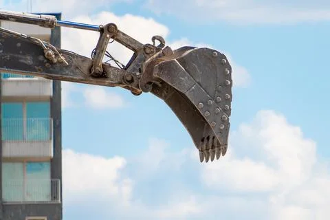 Excavator arm and claw against blue sky and clouds Stock Photos