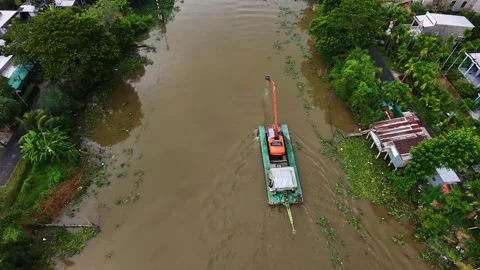 Excavator on a barge navigating a silt-rich canal in the Mekong Delta Stock-Footage 341229670