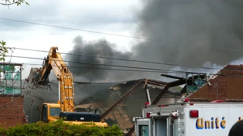 Excavator breaking building while it is on fire in impressive sequence Stock Footage 97682636