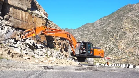 Excavator breaks down the rubble on a mountain road Видео 99851485