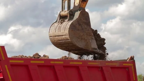 Excavator bucket being dumped into dump truck 스톡 동영상 83630994