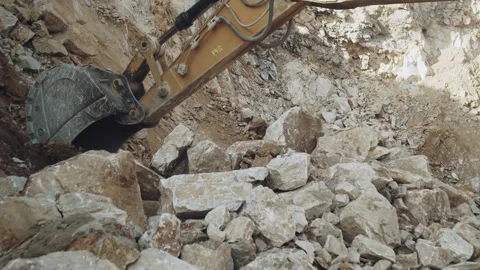 Excavator bucket digging and loading large stone pieces, excavation quarry work Video stock 294080637