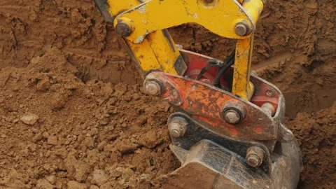 Excavator bucket digging into ground at construction site, moving earth, cl.. Stock Footage 335026524
