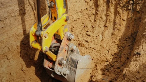 Excavator bucket driven by powerful hydraulics removes soil from the trench Stock Footage 108311771