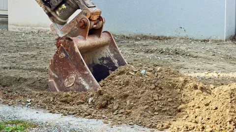 Excavator bucket dumping soil on ground Stock Footage 334410694