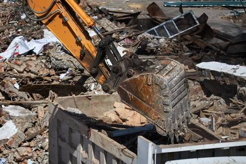 Excavator bucket loading debris into dump truck, demolition and waste management Stock Photos