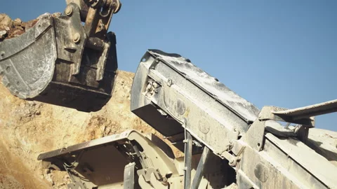 Excavator bucket loading stone pieces in rock crushing machine in quarry Video stock 294079505