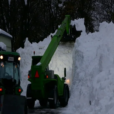 Excavator clearing a huge amount wall of snow from road to unblock the roadway Stock Footage 69556606