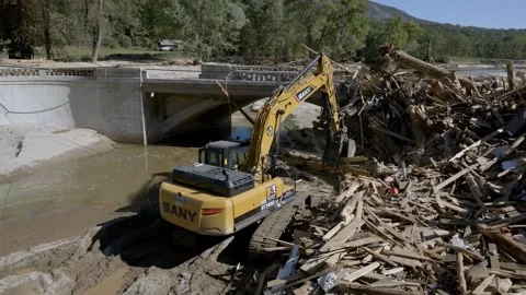 Excavator clearing trees from river left behind from Hurricane Helene Stock Footage 287996552