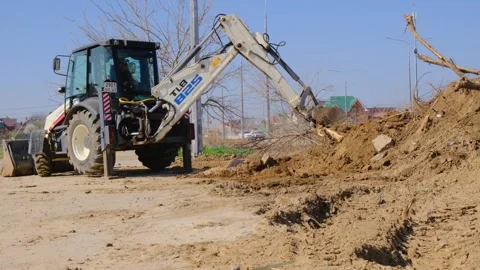 Excavator clears an illegal dump of garbage and dead trees. Mechanized cleaning Video stock 321873418