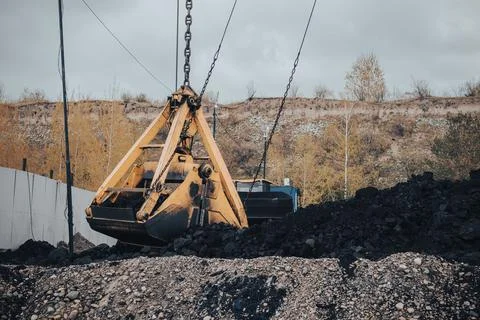 Excavator crane is engaged in loading and unloading coal busy mining site. Large Stock Photos