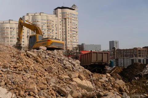 An excavator on a destroyed building. Loading a dump truck with construction  Stock Photos
