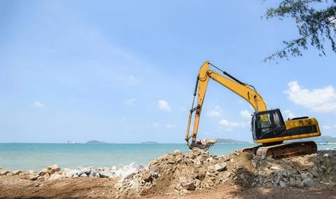 Excavator digger stone working on construction site - backhoe loader on the.. Stock Photos