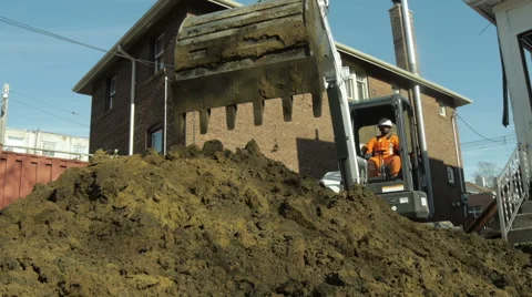 Excavator Digging and Dumping Large Pile of Soil with house in background 库存影片 40648774