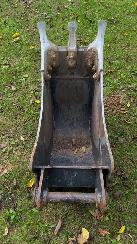Excavator digging bucket attachment resting on grass  Vídeos de archivo 347516136
