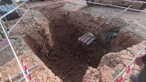 Excavator Digging Deep Hole for Electrical Manhole Installation with Safety Tape Stock Footage 340985896