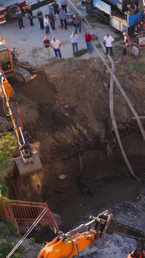 Excavator digging deep pit for major sewer pipe repair Stock Footage 344179327