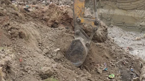 An excavator digging into a dirt pile Stock Footage 304057640