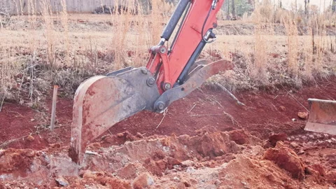 Excavator digging in red soil at construction site 스톡 동영상 338115770