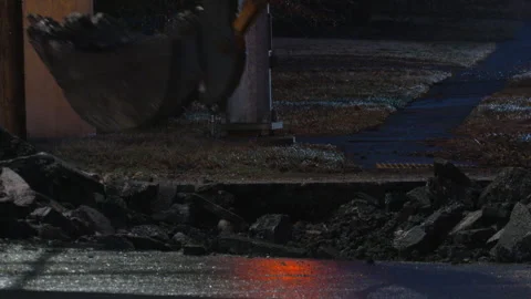 Excavator digging up road pavement at night Stock Footage 252139926