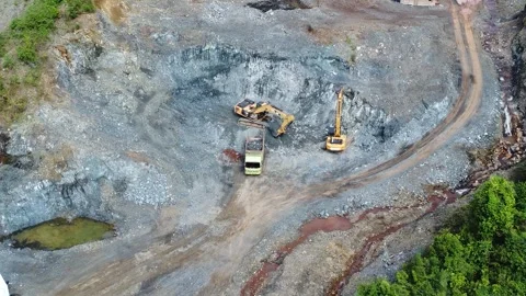 Excavator digging rocks to be loaded onto a truck in a stone mining area, b.. Stock Footage 312297797