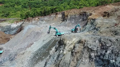 Excavator digging rocks to be loaded onto a truck in a stone mining area, b.. Stock Footage 312298821