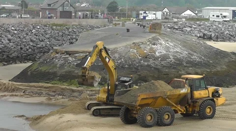 An excavator is digging up sand and is loading it onto a lorry Stock Footage 57536772