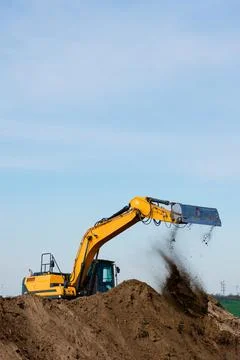 Excavator digging sand on construction site vertical shot Photos
