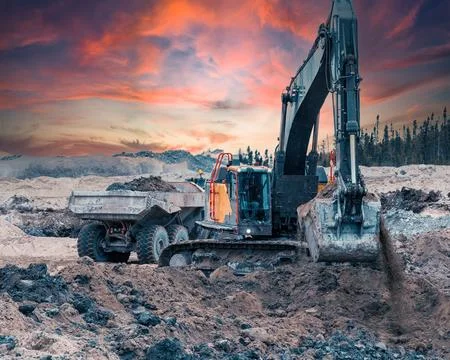 Excavator digging soil on a site at sunset Stock Photos